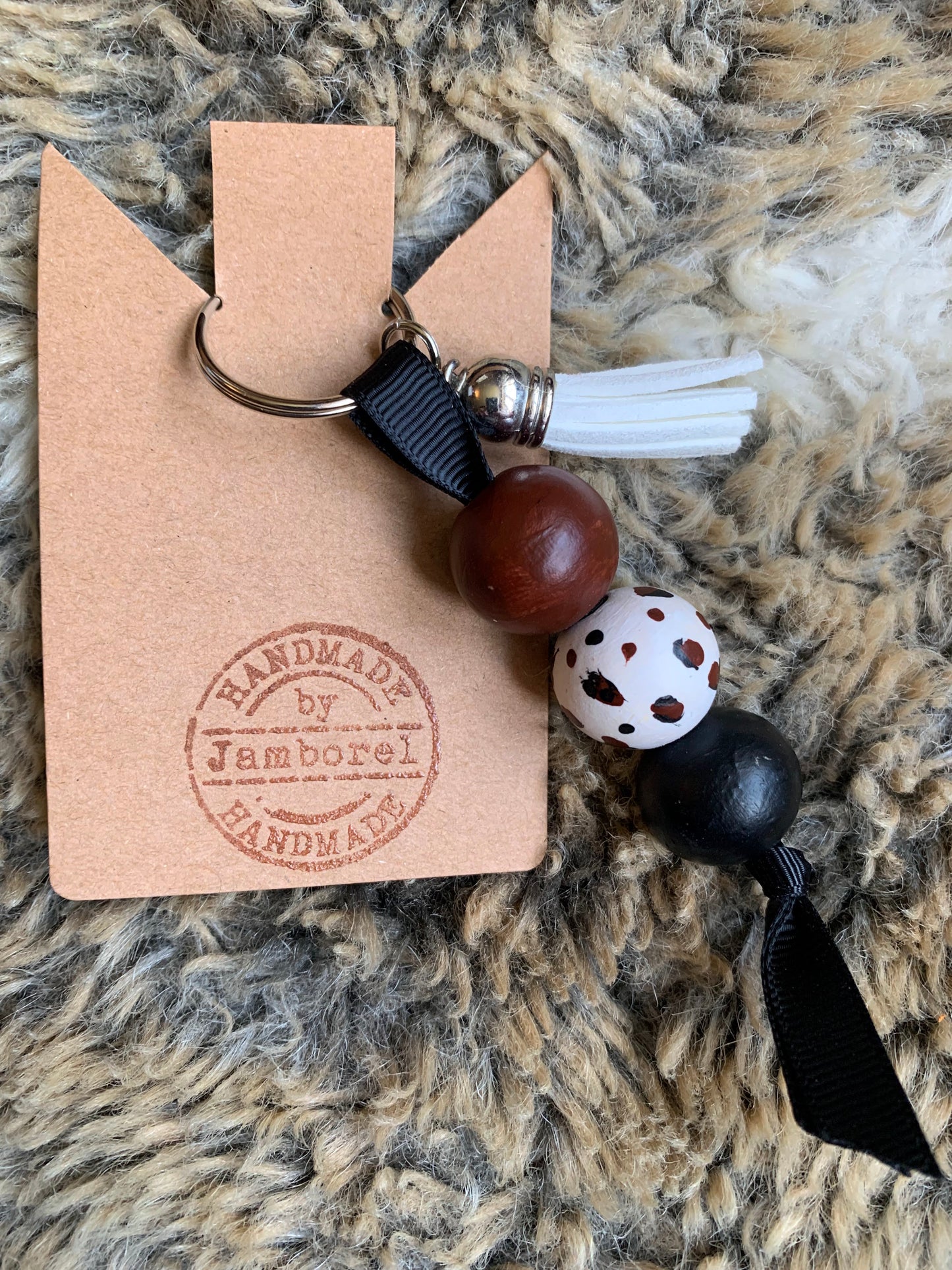 Wooden beads hand-painted with a leopard print design attached to a keyring with a faux-leather tassle